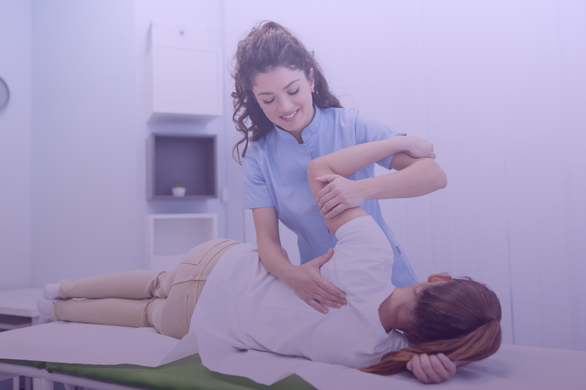 Ein Physiotherapeut dehnt den Arm eines Patienten auf einer Untersuchungsliege in einer Klinik.