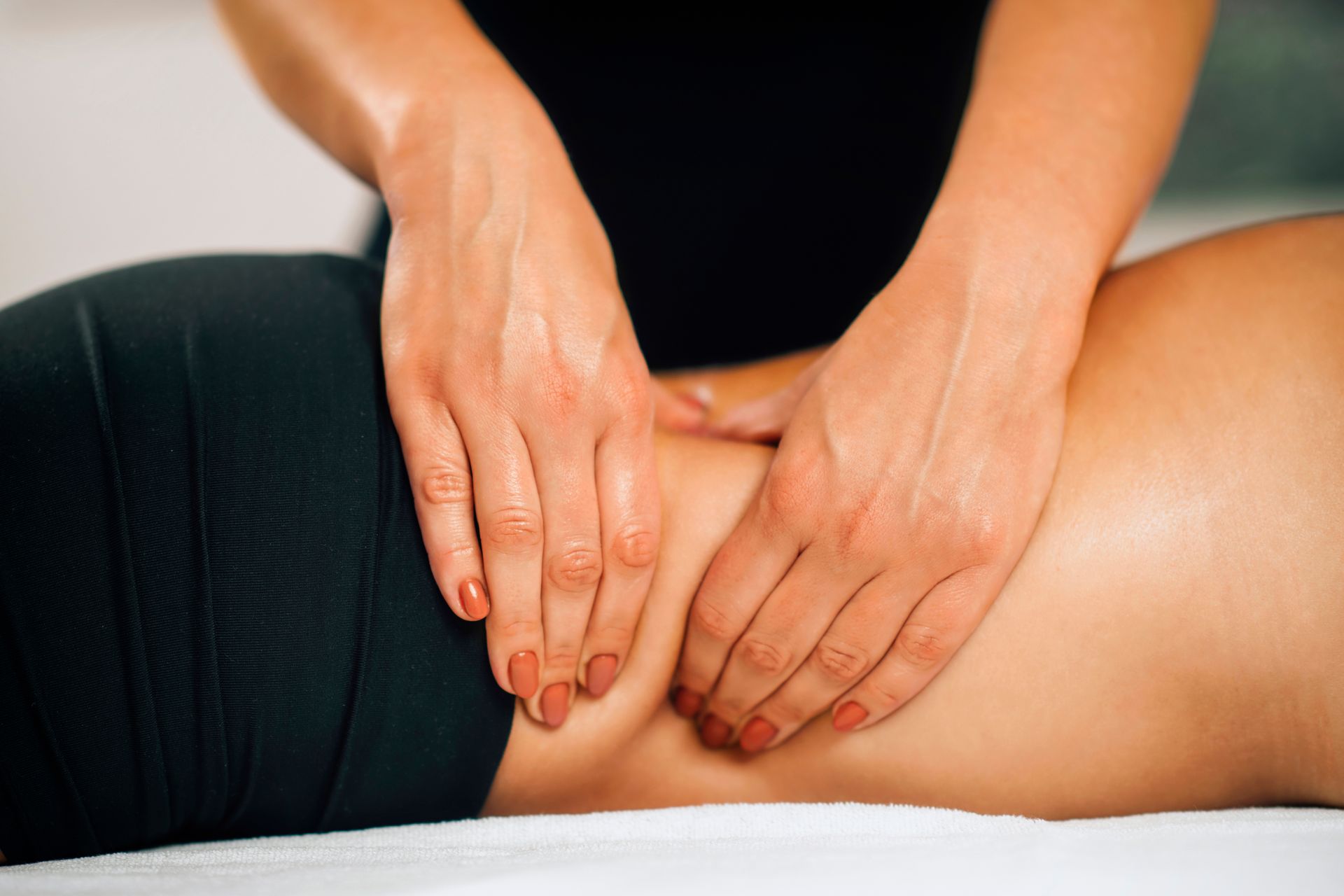 Hands performing a back massage on a person lying face down on a table.