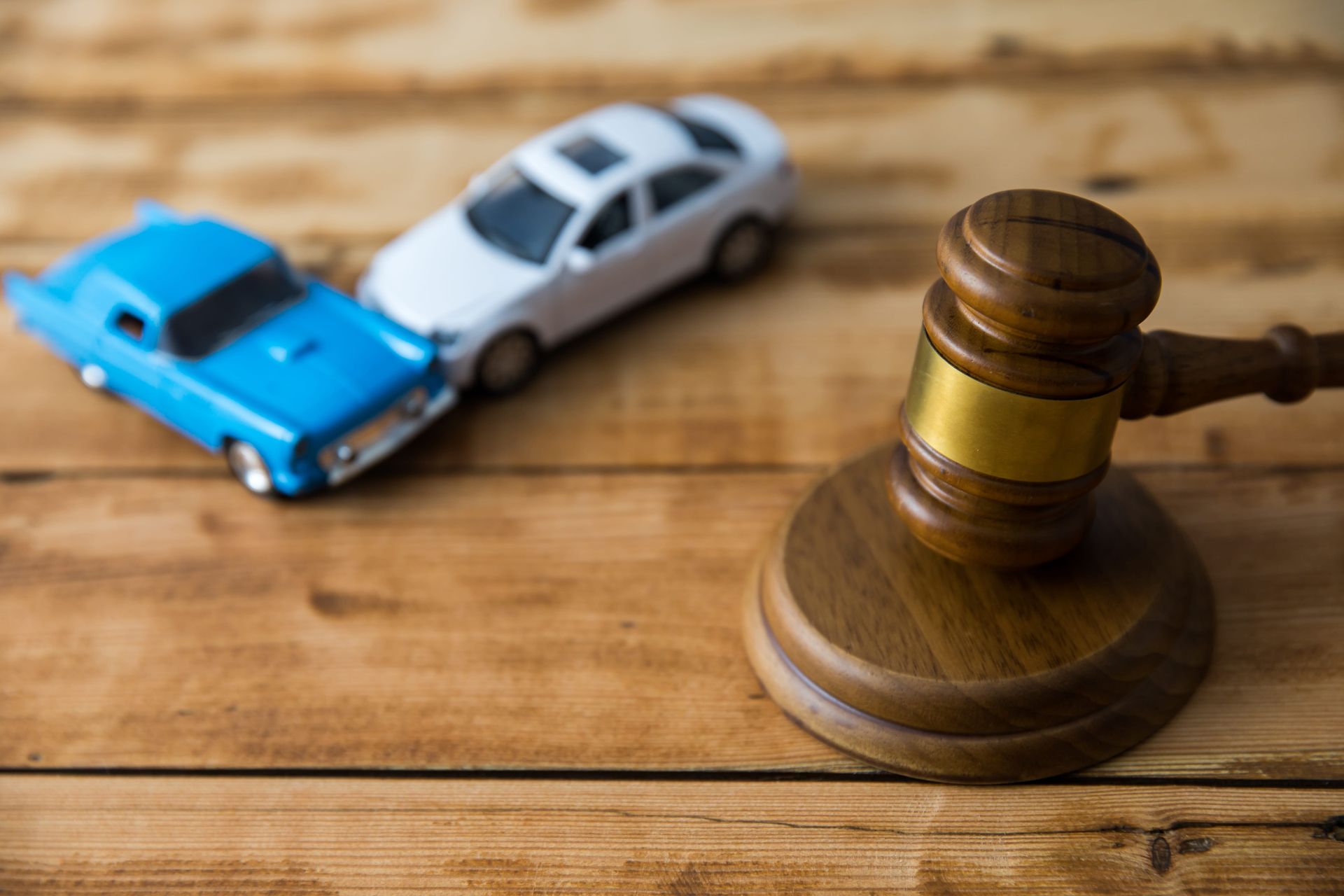 Toy cars colliding beside a wooden judge’s gavel on a table