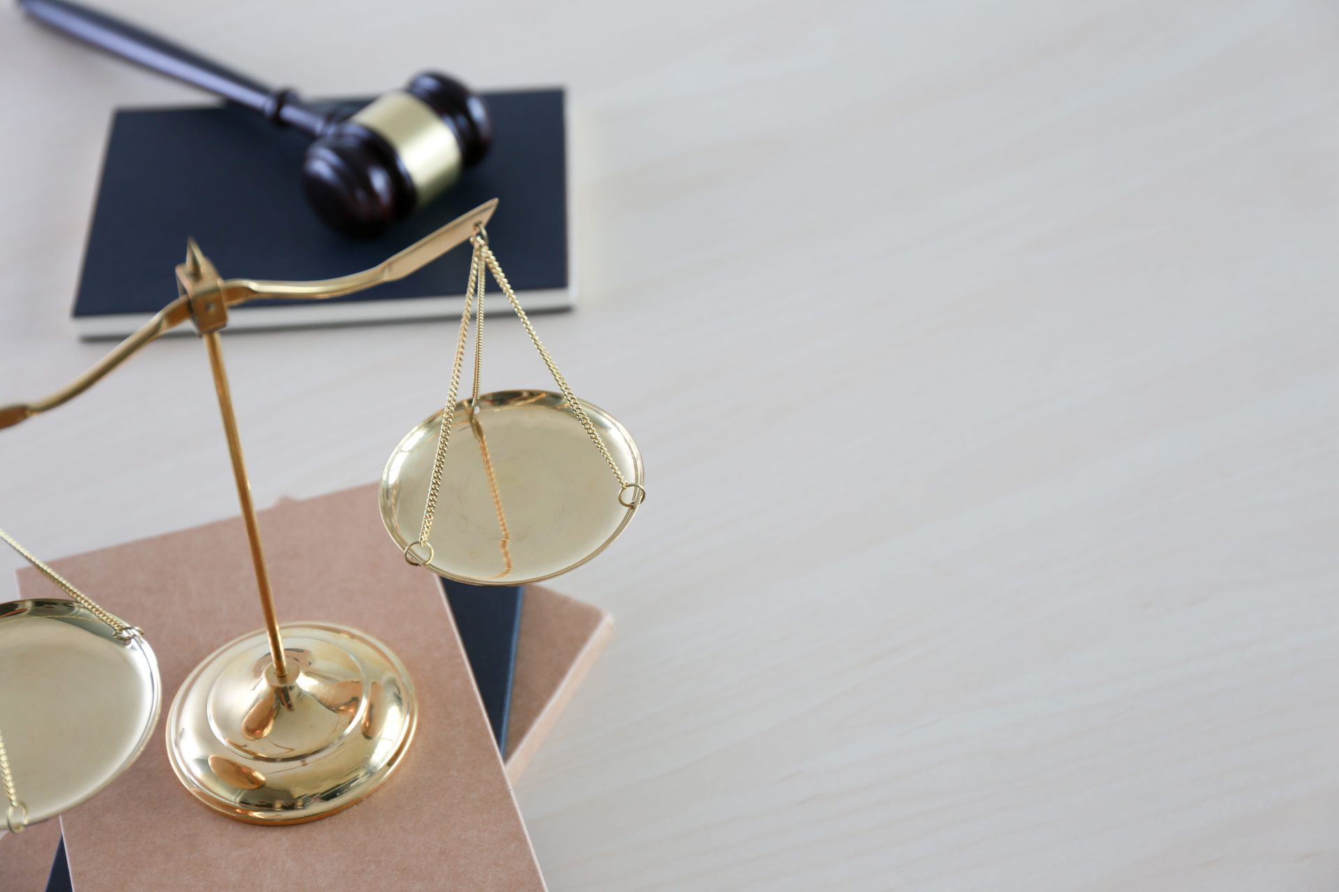 Gold balance scale on a desk with a gavel in the background