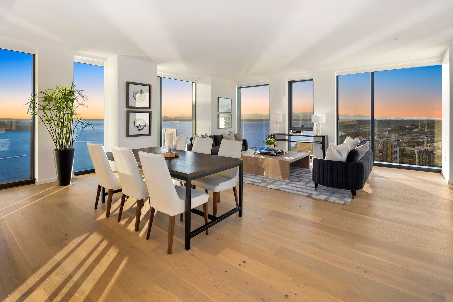 Bright modern dining and living room with large windows, city view, and wood floors.