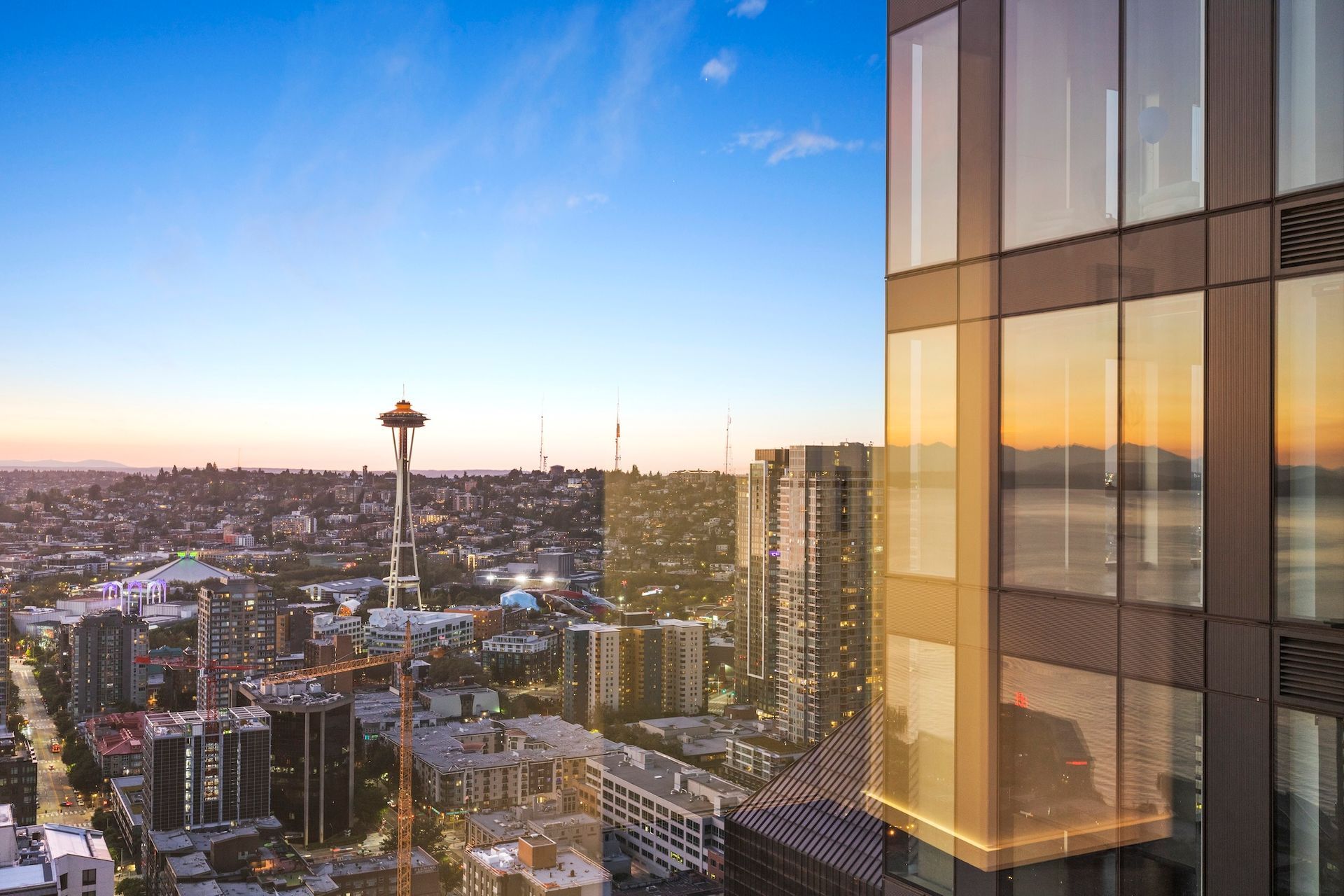 Seattle skyline at sunset with the Space Needle and a glass high-rise reflecting warm light