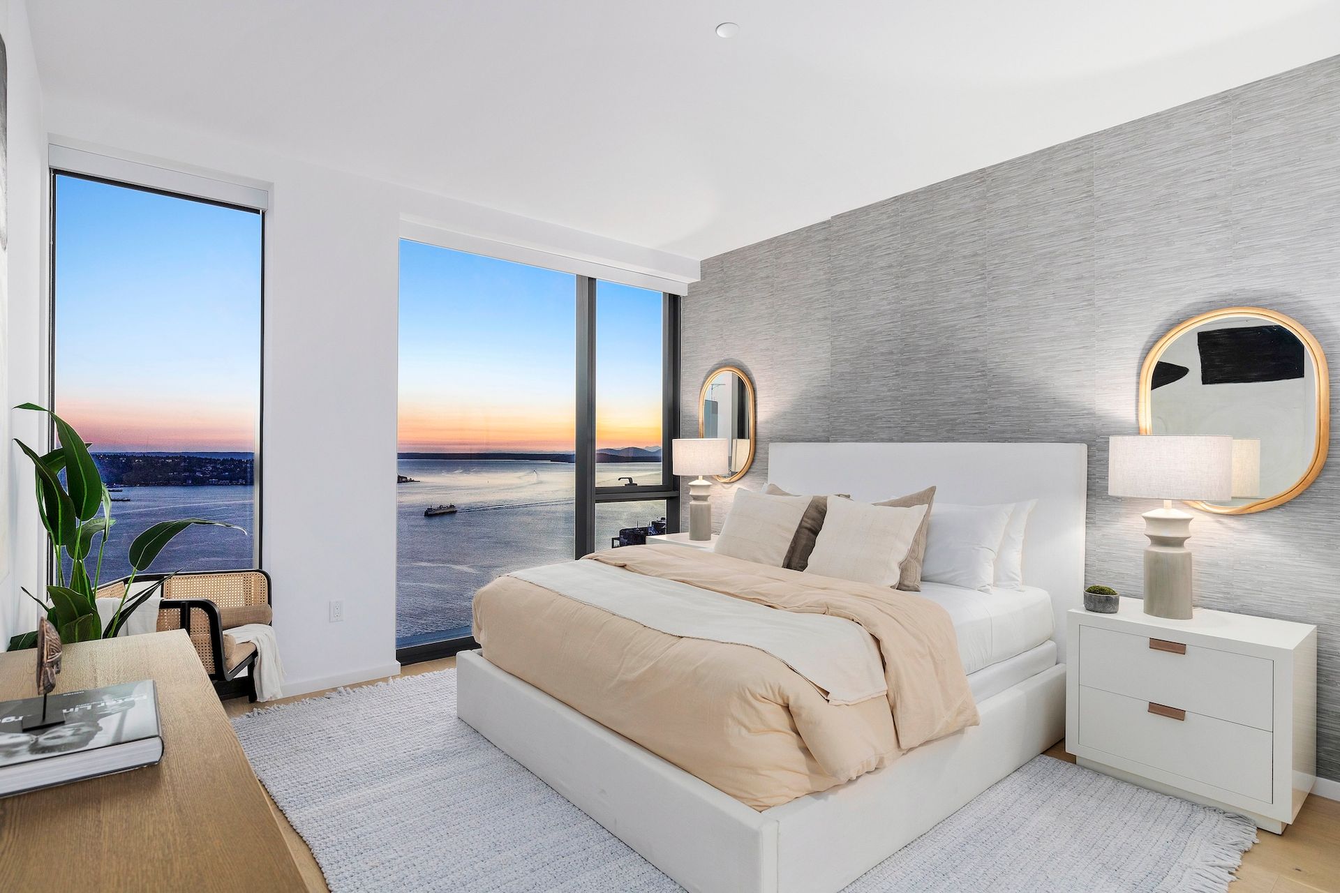 Modern bedroom with king bed, floor-to-ceiling windows, and ocean sunset views.