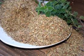 A white plate topped with dried herbs and a sprig of mint on a wooden table.