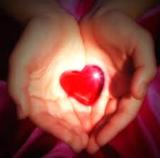 A person is holding a red heart in their hands.