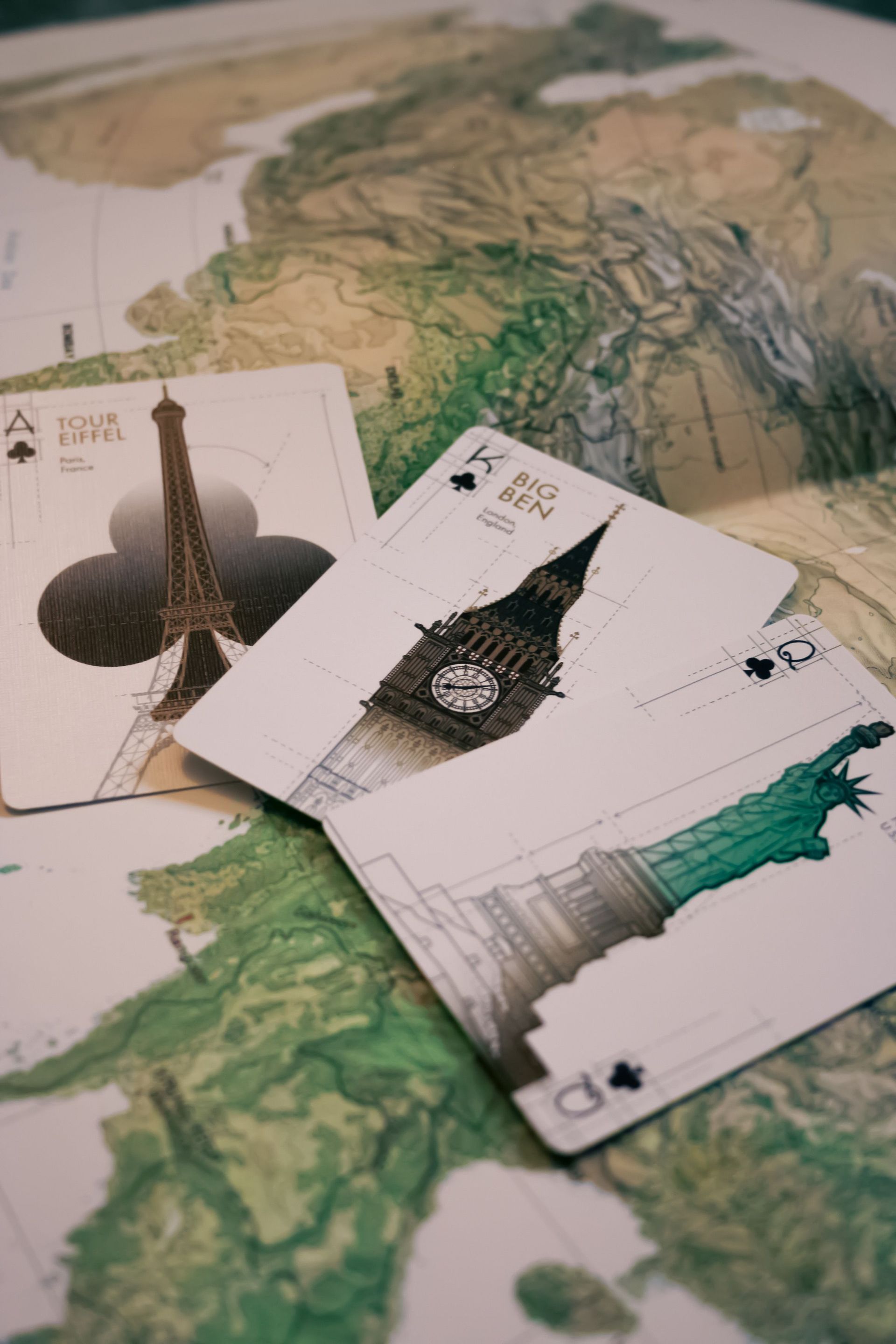 Three overlapping cards on a topographic map, showing black and green abstract designs.