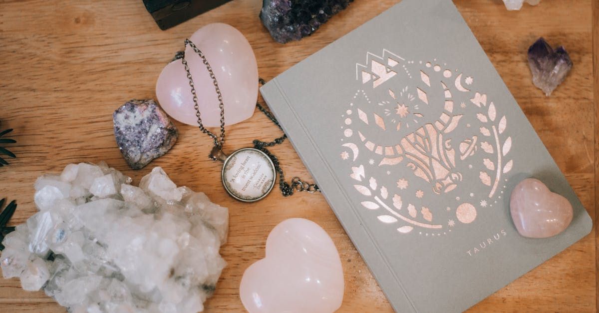 A book surrounded by crystals and a necklace on a wooden table.