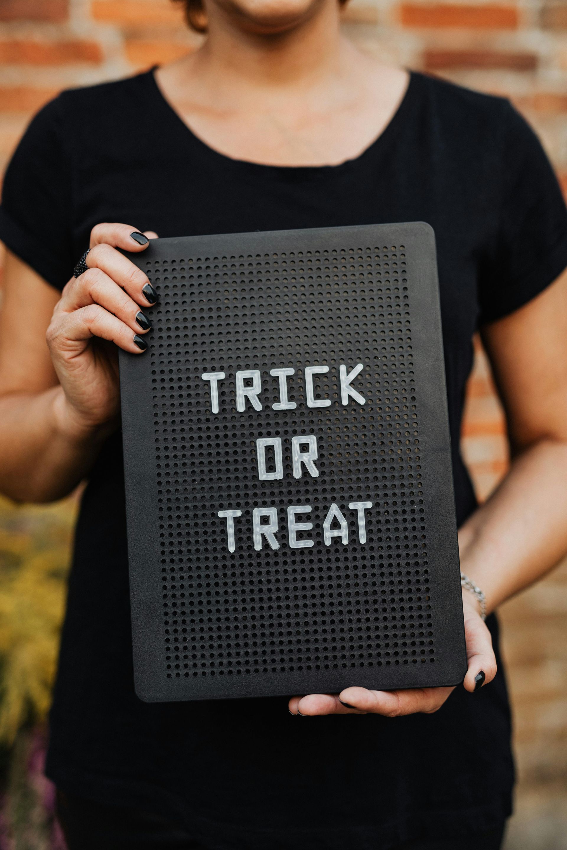 A woman is holding a sign that says trick or treat.
