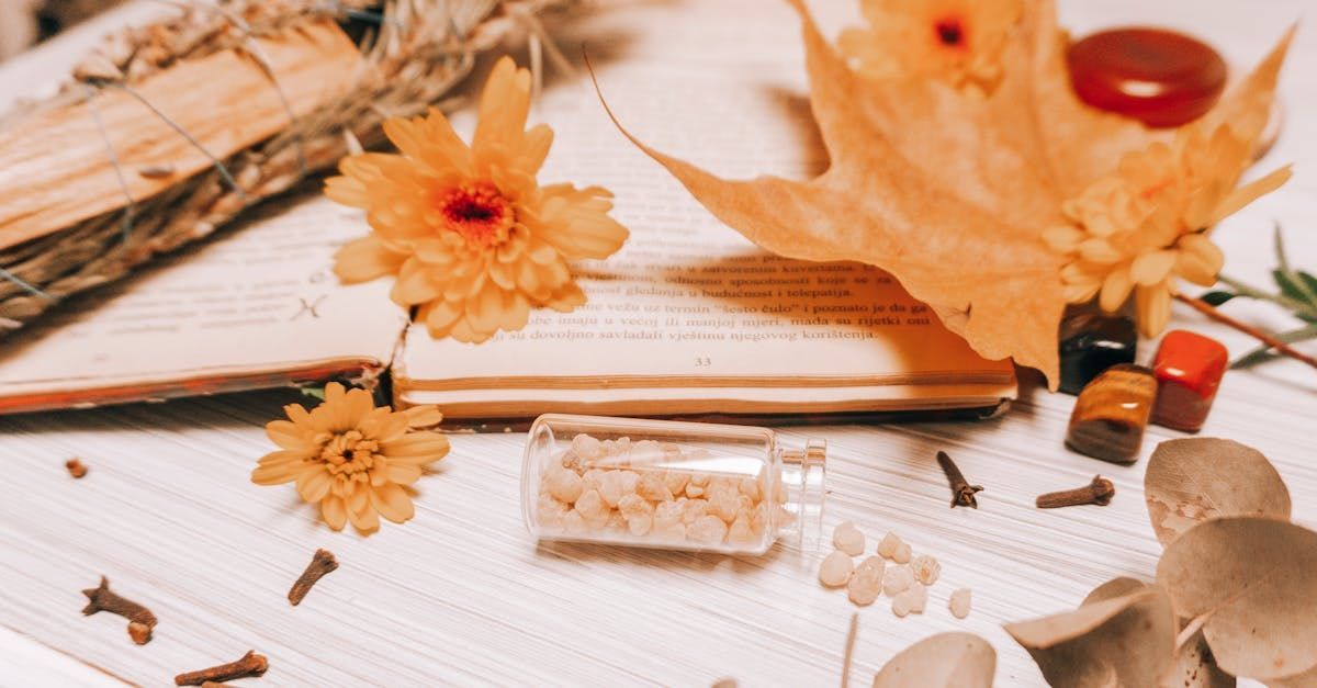 A bottle of flowers is sitting on top of a book on a table.