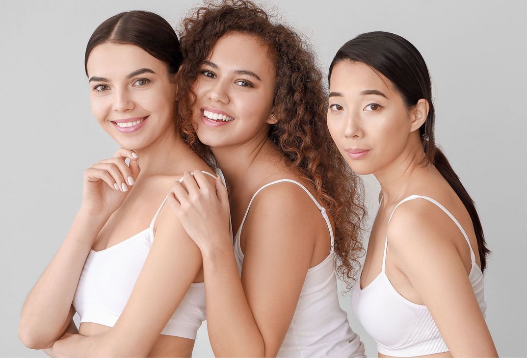 Three women are posing for a picture together and smiling.