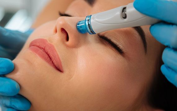 A woman is getting a facial treatment with a machine on her face.
