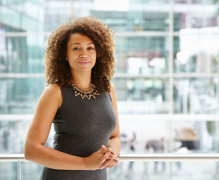 A woman with curly hair is standing in front of a window.