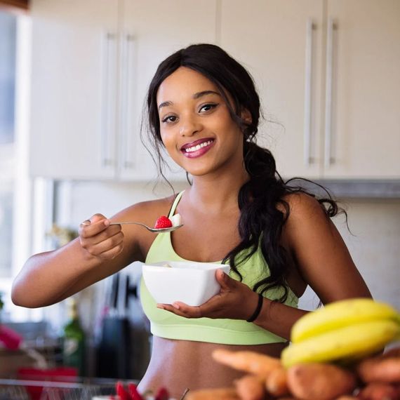 A woman is eating a bowl of cereal in a kitchen.