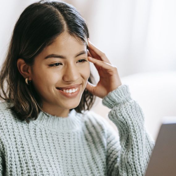 A woman is sitting on a couch using a laptop computer.