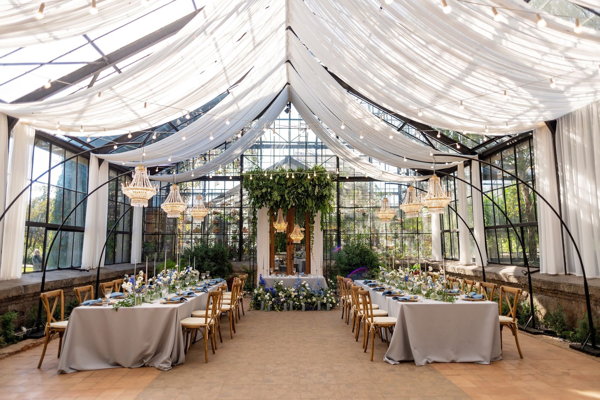 A large greenhouse with tables and chairs set up for a wedding reception.