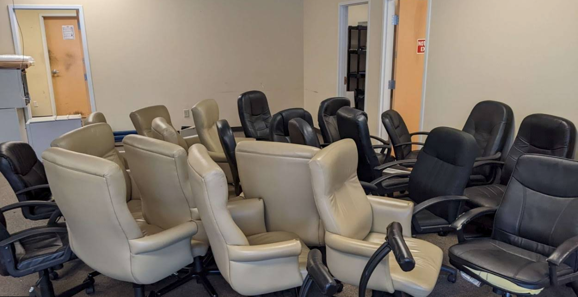 A room filled with rows of black, beige, and gray recliner chairs, like a showroom or office waiting area.
