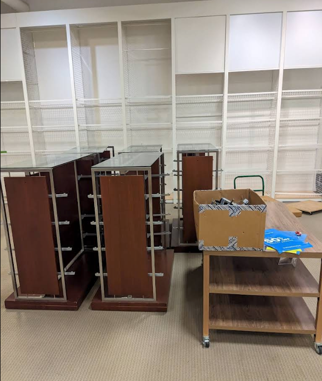 Empty library shelves and overturned wooden book carts in a room.