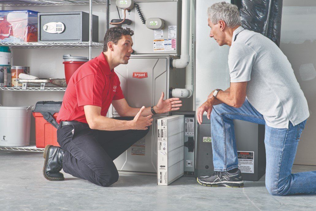 Two men are kneeling down in front of a furnace.