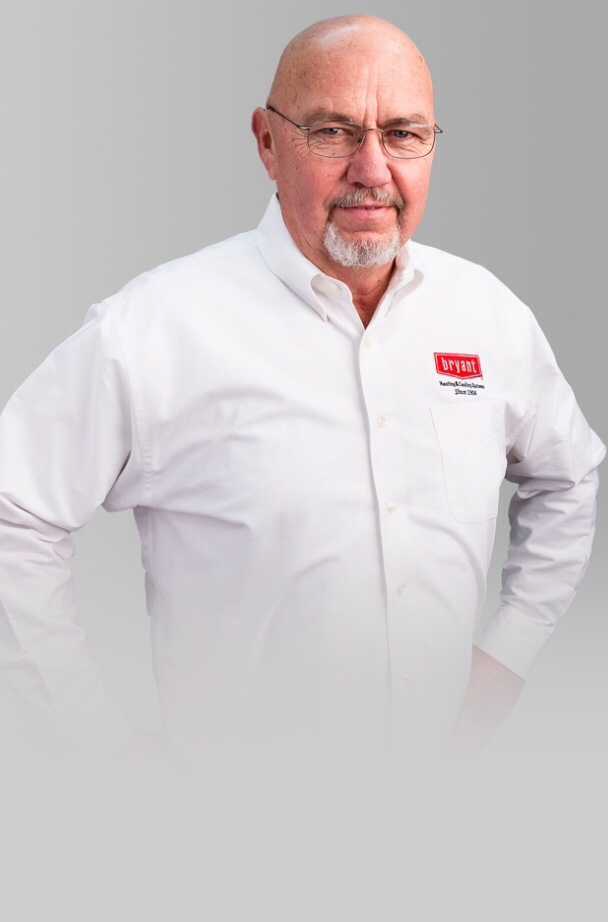 A man with glasses and a beard is wearing a white shirt with a red logo on it.