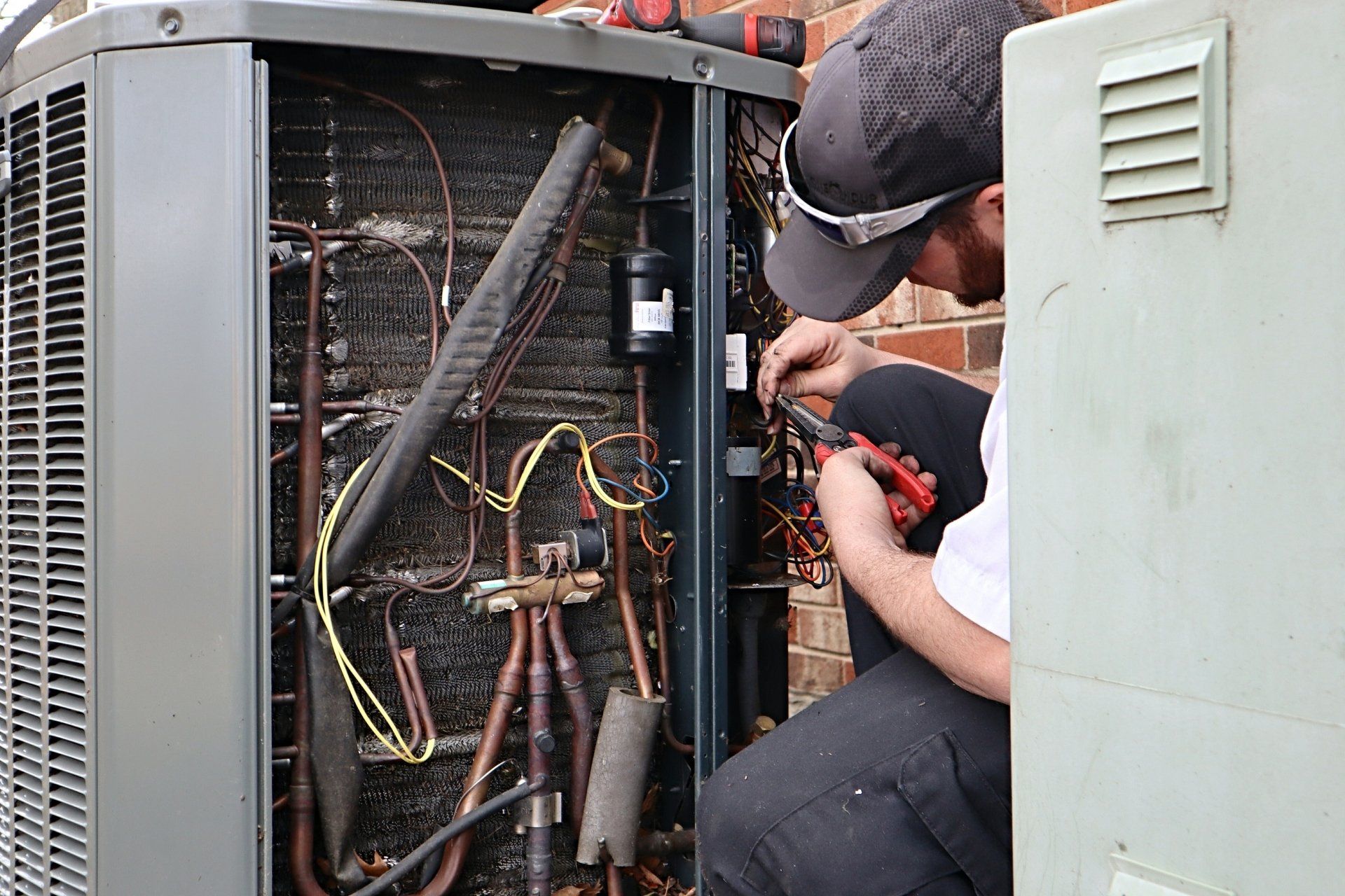 A man is working on an air conditioner outside of a building.