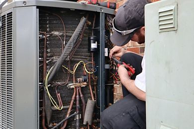 A man is working on an air conditioner outside of a building.