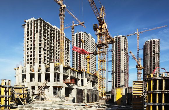 A construction site with a lot of cranes and buildings under construction.