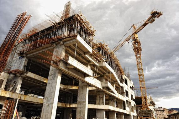 A large building is under construction with a crane in the foreground.