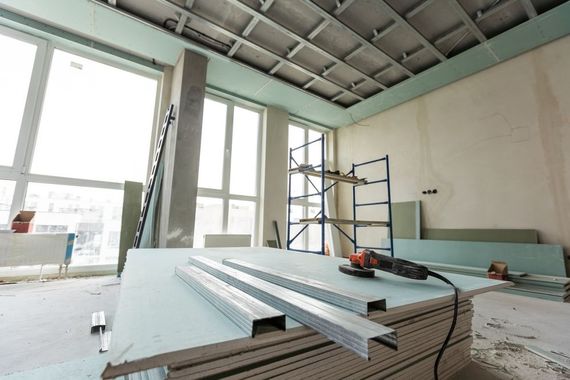 A room under construction with a stack of drywall and a drill.