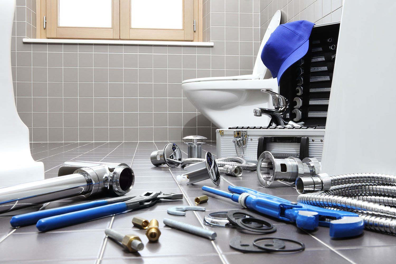 A bathroom with a toilet and a bunch of plumbing tools on the floor.