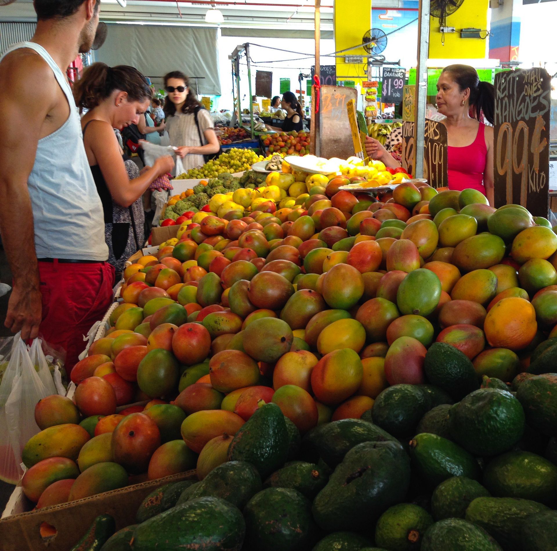 Colourful tropical fruit stall at Rustyโs Markets in Cairns CBD, Queensland, featuring ripe mangoes, avocados and local produce with visitors shopping indoors, showcasing Rustyโs Markets as a must-visit wet-season attraction and authentic food experience in Far North Queensland.