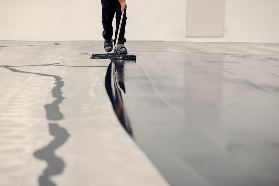 Person mopping a glossy floor with dark and light reflections visible