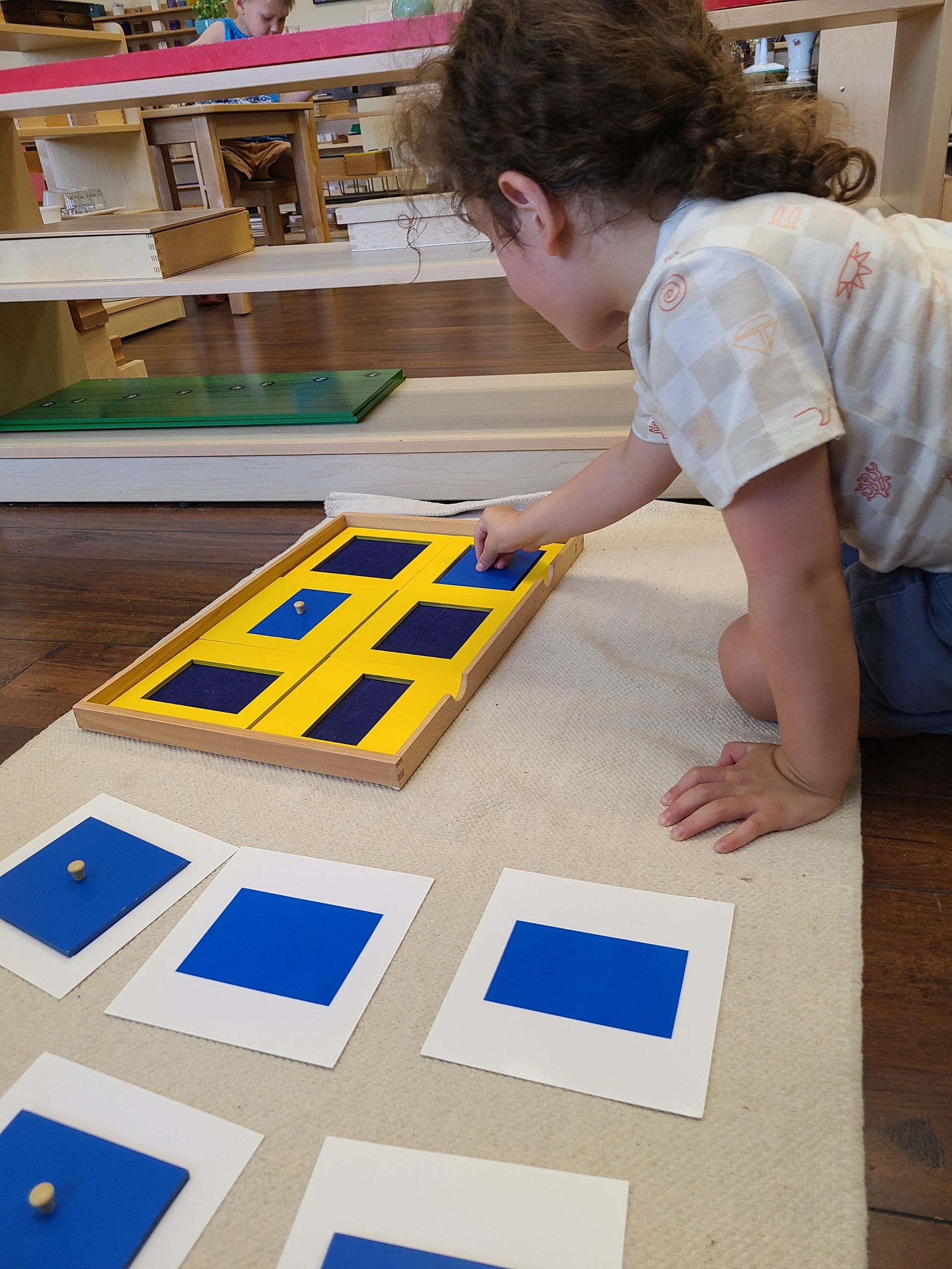 Child working with the Montessori geometry cabinet on a working mat