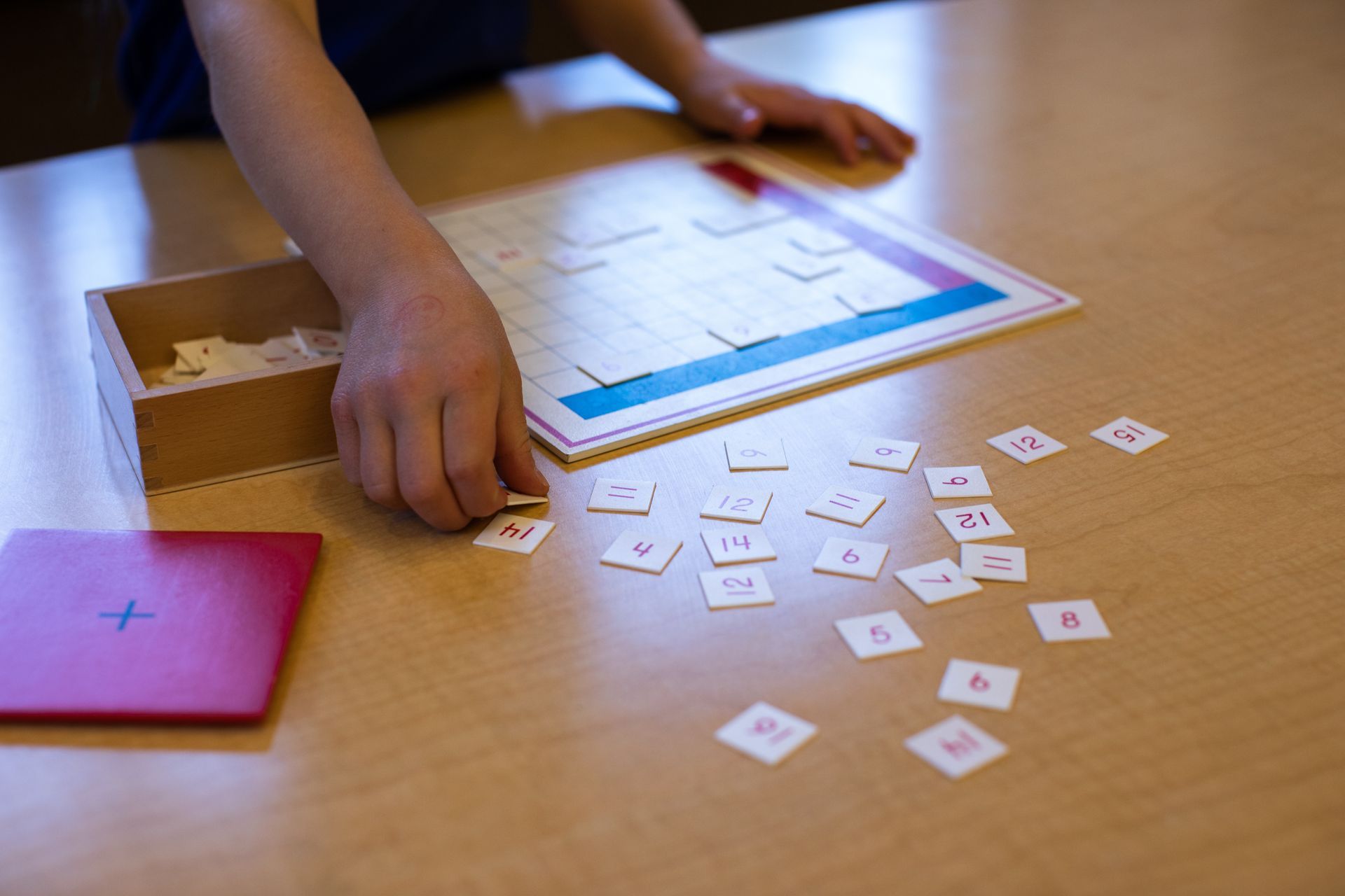 A child working with the addition finger chart on a wooden table