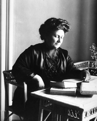 Dr. Maria sitting at a table reading a book.