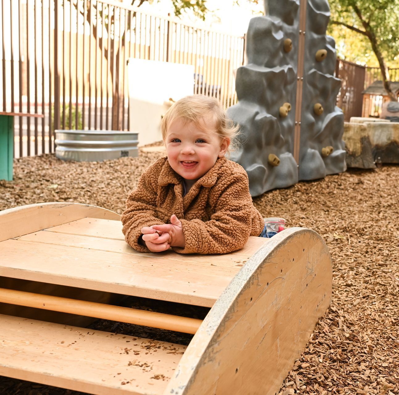 Montessori infant on wooden play structure at a playground.