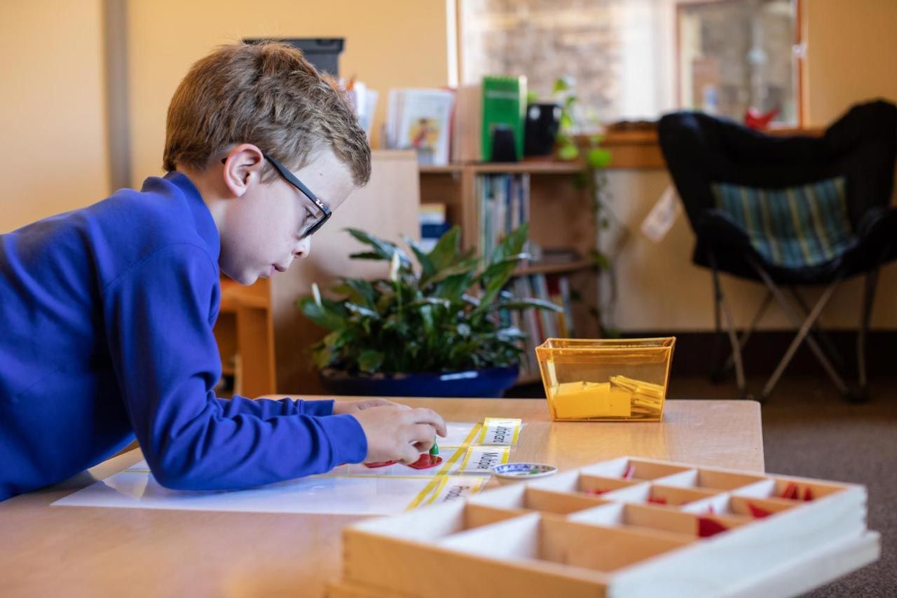 A Montessori student is sitting at a table working with Montessori language materials.
