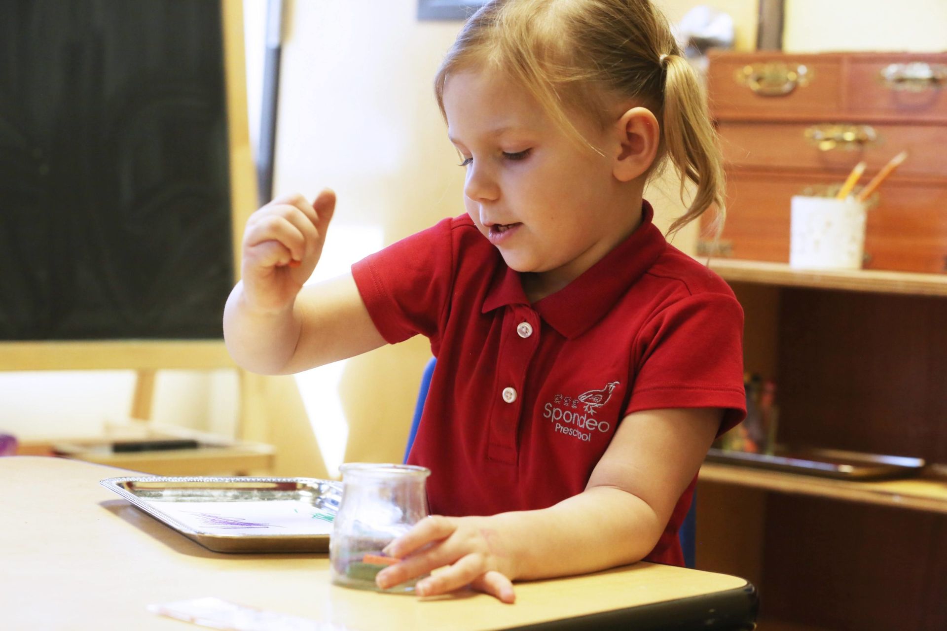 Montessori child is working in the classroom with Montessori materials