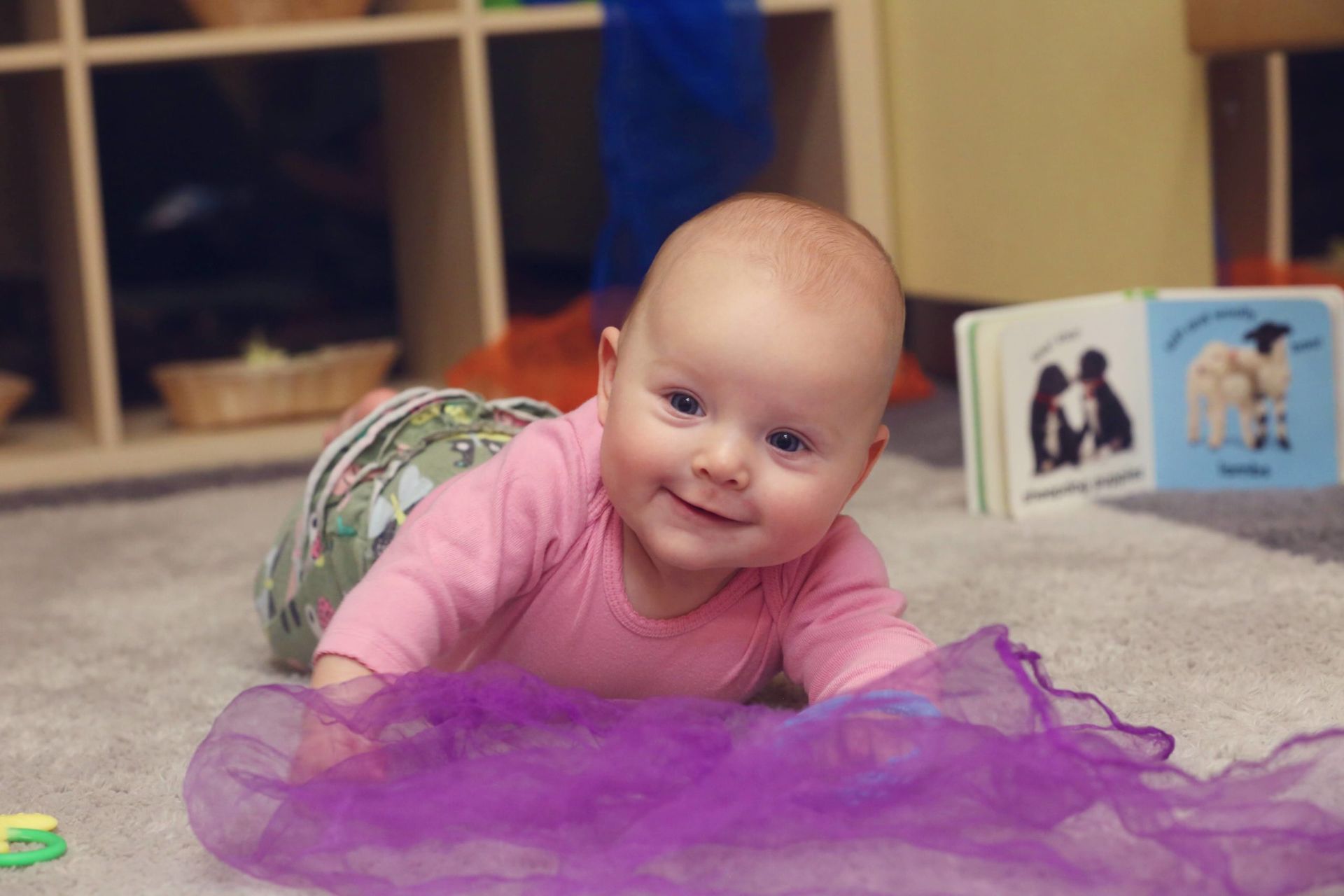 Montessori Infant is laying on a carpet smiling