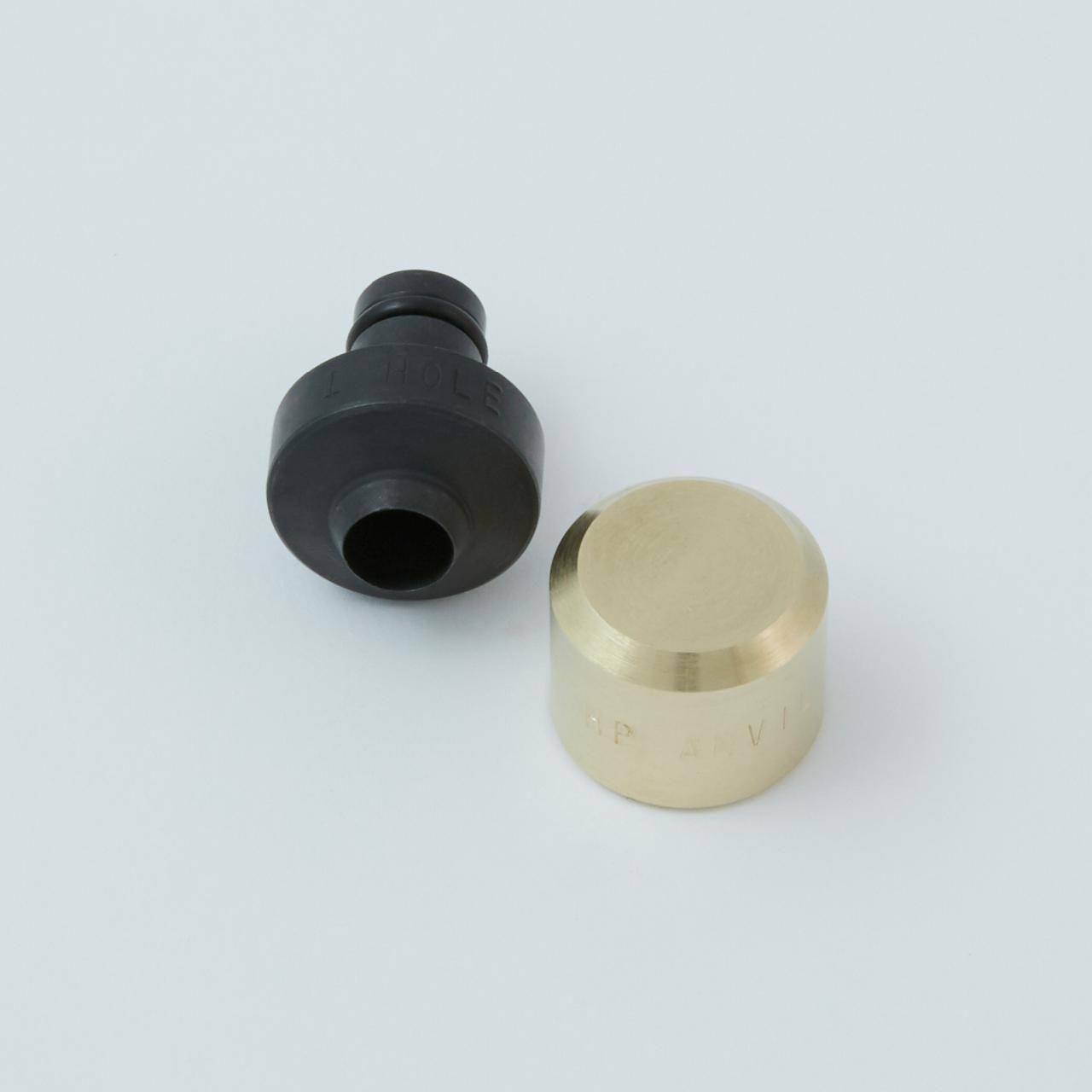 Two mechanical parts: a black, cylindrical piece and a brass, rounded cylinder.