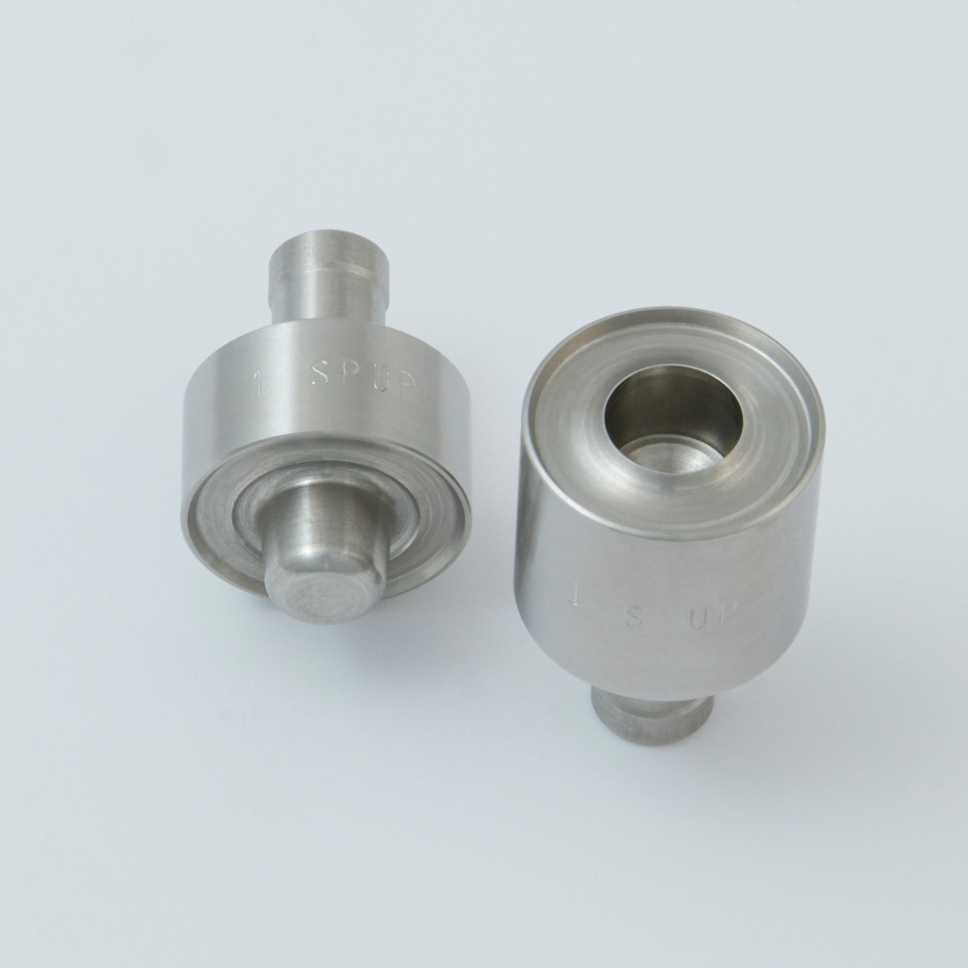 Two silver metal cylindrical parts with threaded ends on a light background