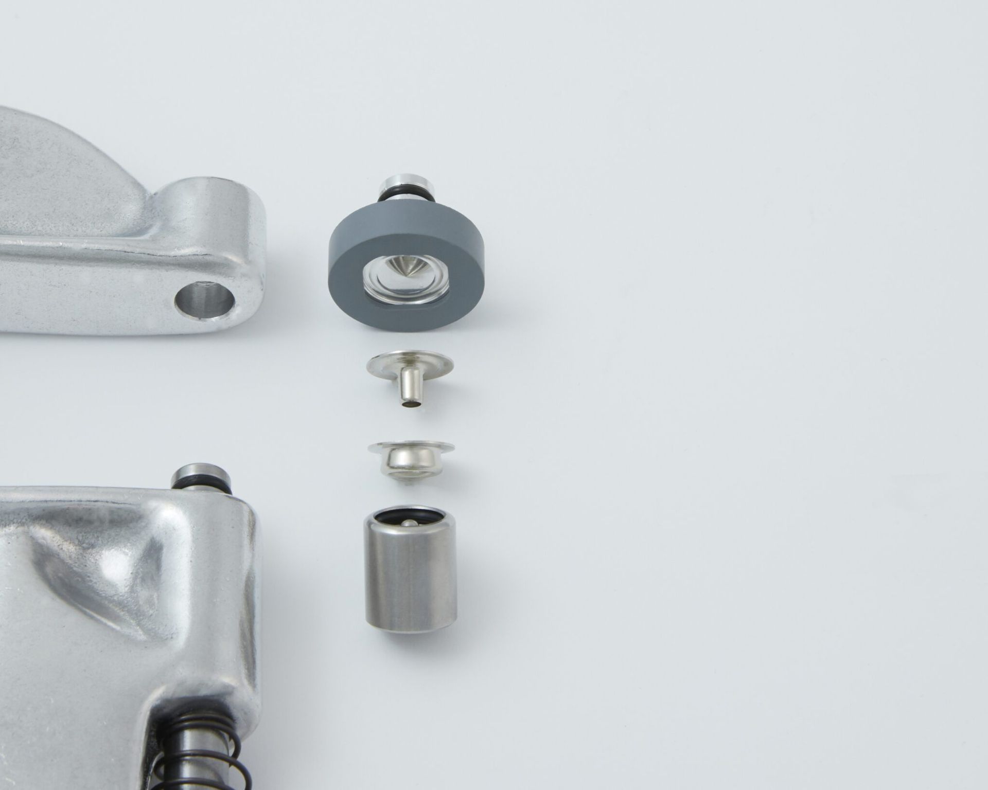 Exploded view of metal tool parts, including a rubber wheel, various metal fasteners, and two sections of a tool handle.