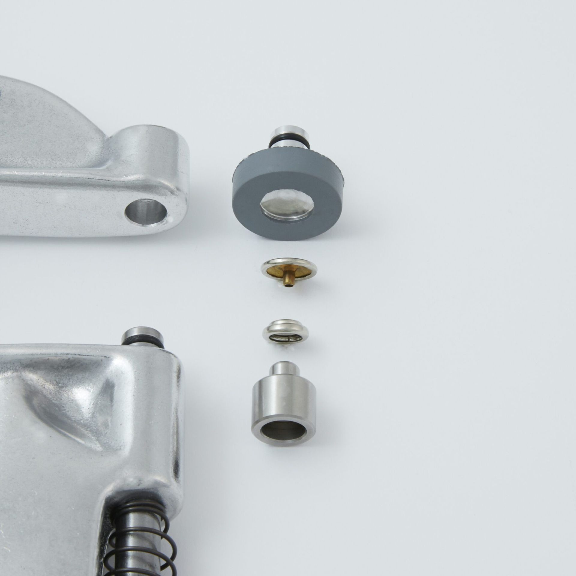 Exploded view of a mechanical component, showing various metal and rubber parts disassembled on a white surface.