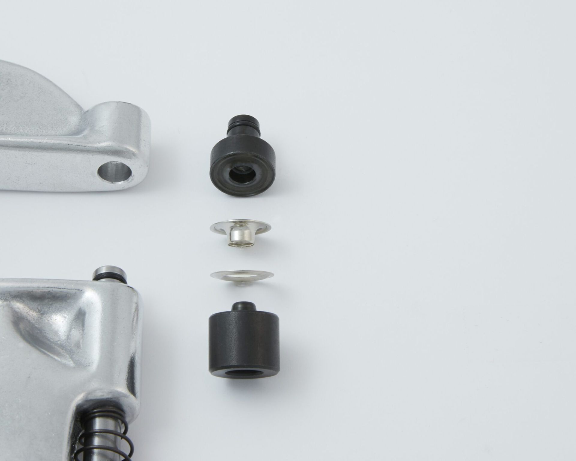 Parts of a rivet press, including punches, dies, and a rivet, on a white background.