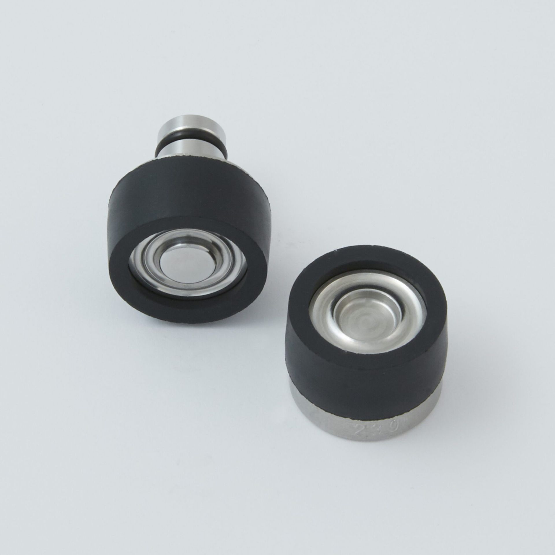 Two black-and-silver cylindrical camera lens adapters on a white surface