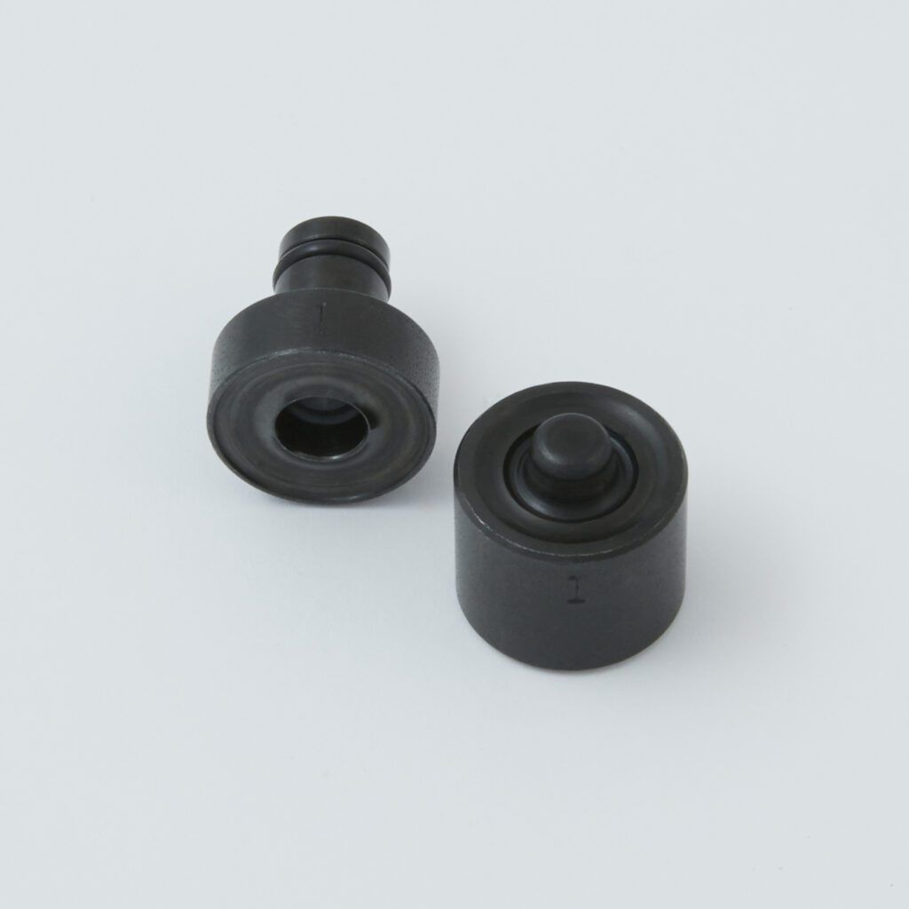 Two black cylindrical plastic parts, one upright and one lying on its side, on a light gray background