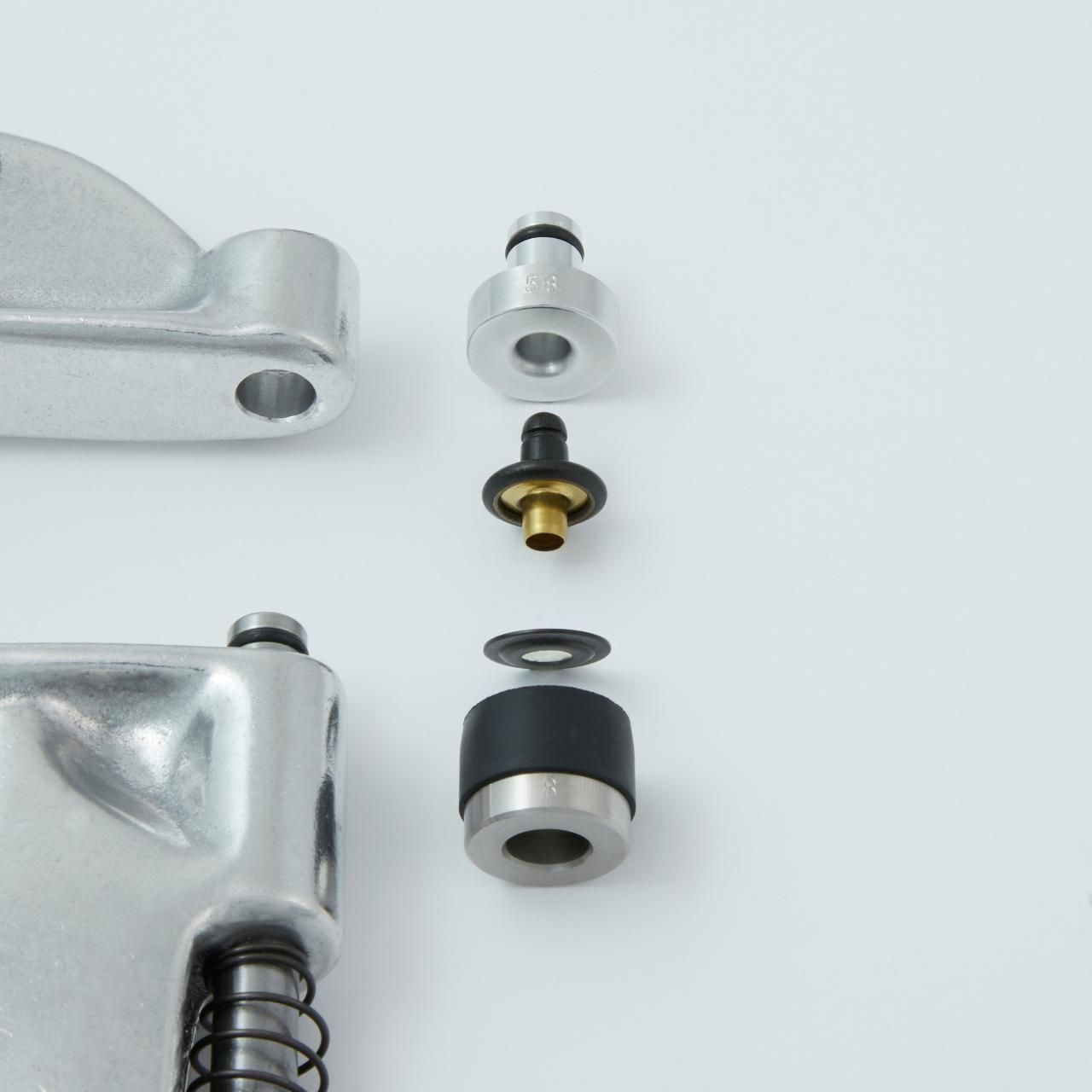 Exploded view of a mechanical component, showing a cylinder with associated parts: a valve, seal, and retainer.