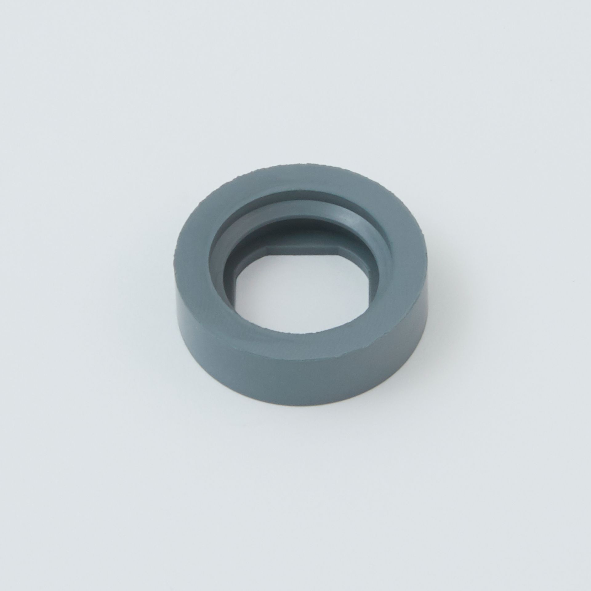 Gray rubber grommet with a central hole on a light background