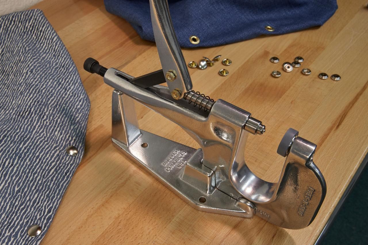 Silver eyelet press with leather and denim, small brass eyelets.