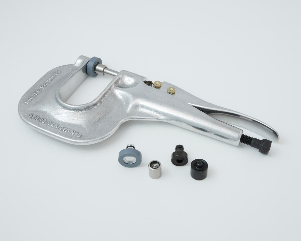 Metal grommet tool with interchangeable dies and a light gray finish.