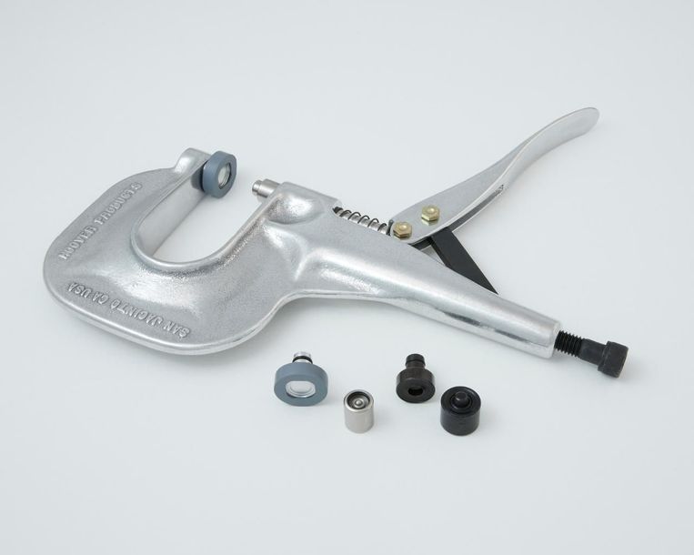 Hand press tool with interchangeable dies for setting rivets or snaps.
